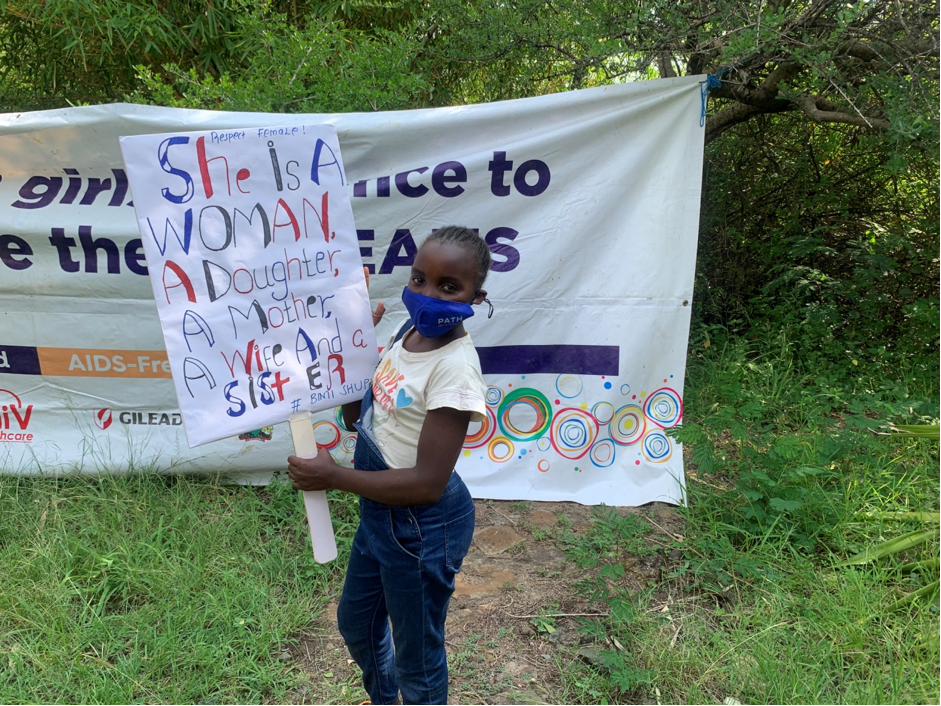 An AGYW carrying a banner advocating for equal rights of the girl child in the Digital Space; during the celebration of the international day of the girl child in Kasgunga ward.